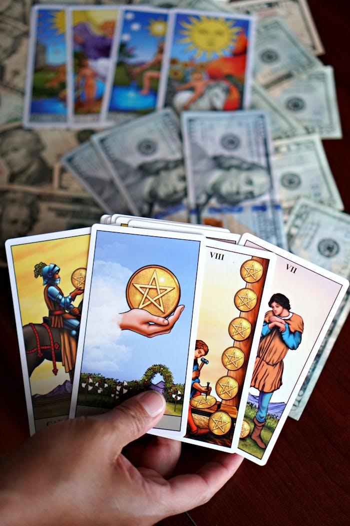 Colorful tarot cards held over a background of scattered dollar bills, symbolizing fortune.